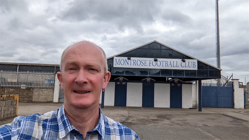 Self portait photo in front of the entrance gates at the Montrose Football Club ground
